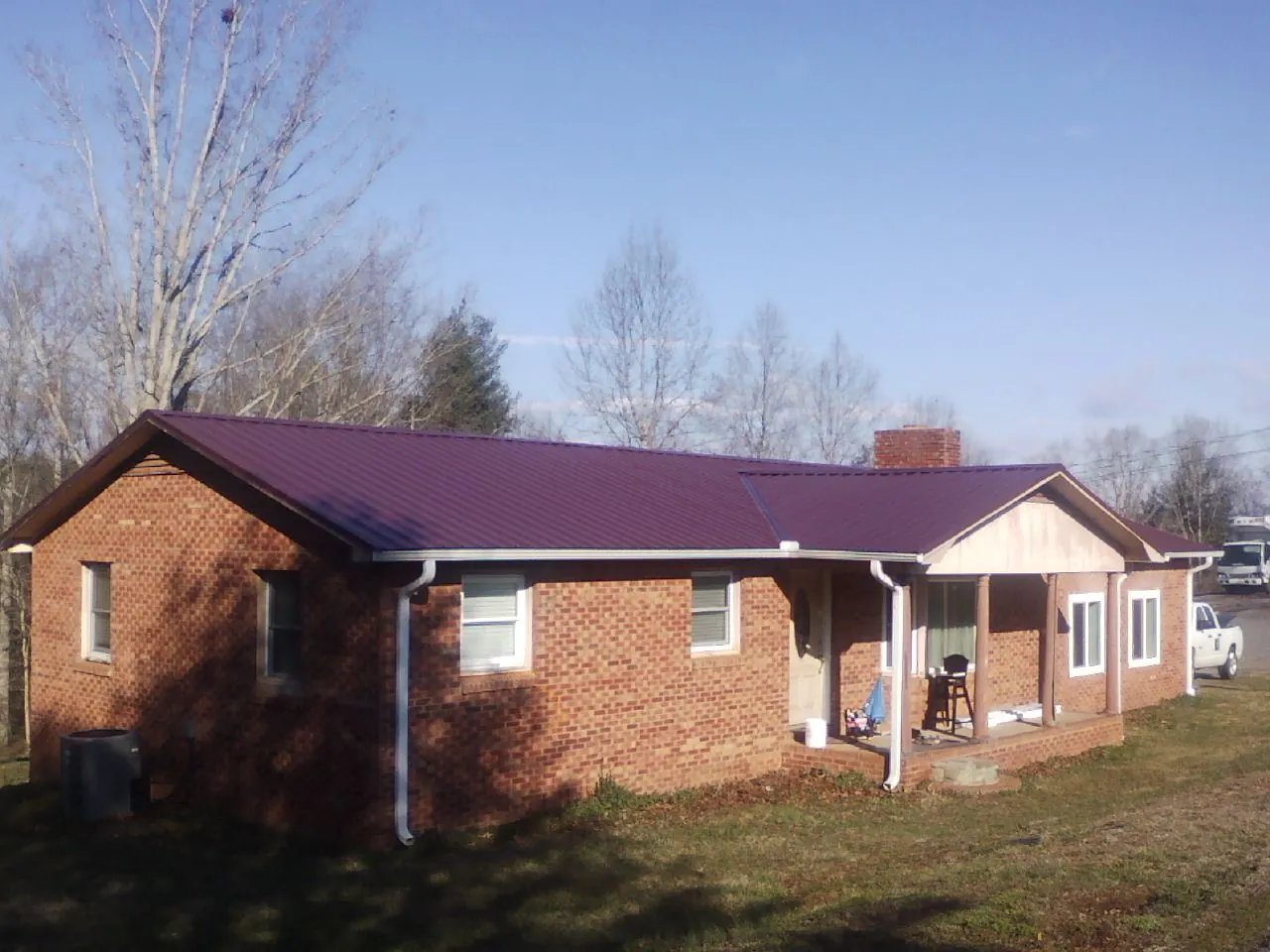 Burgundy metal roof on a brick ranch home with a new addition in Saint Clairsville