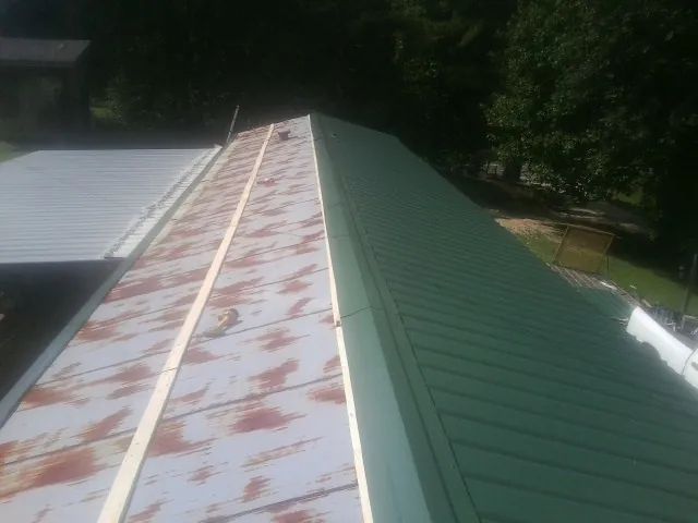 Old rusted panels beside newly installed green metal roofing — Wind Damage Roof Repair by Roofing Brothers in Saint Clairsville
