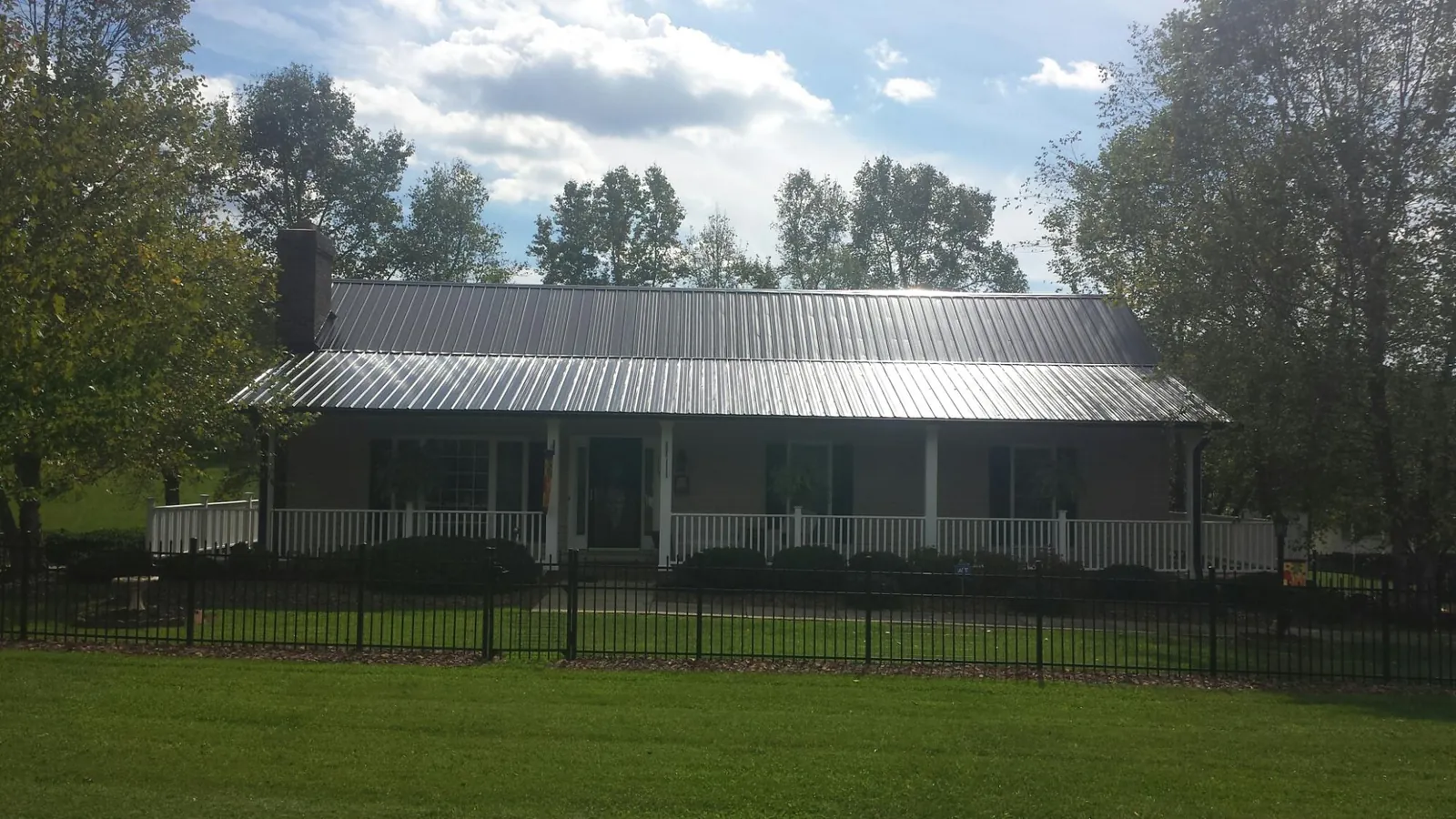 Gray metal roof on a brick ranch with a full width front porch — Gutter Guard Installation work by our crew in Saint Clairsville