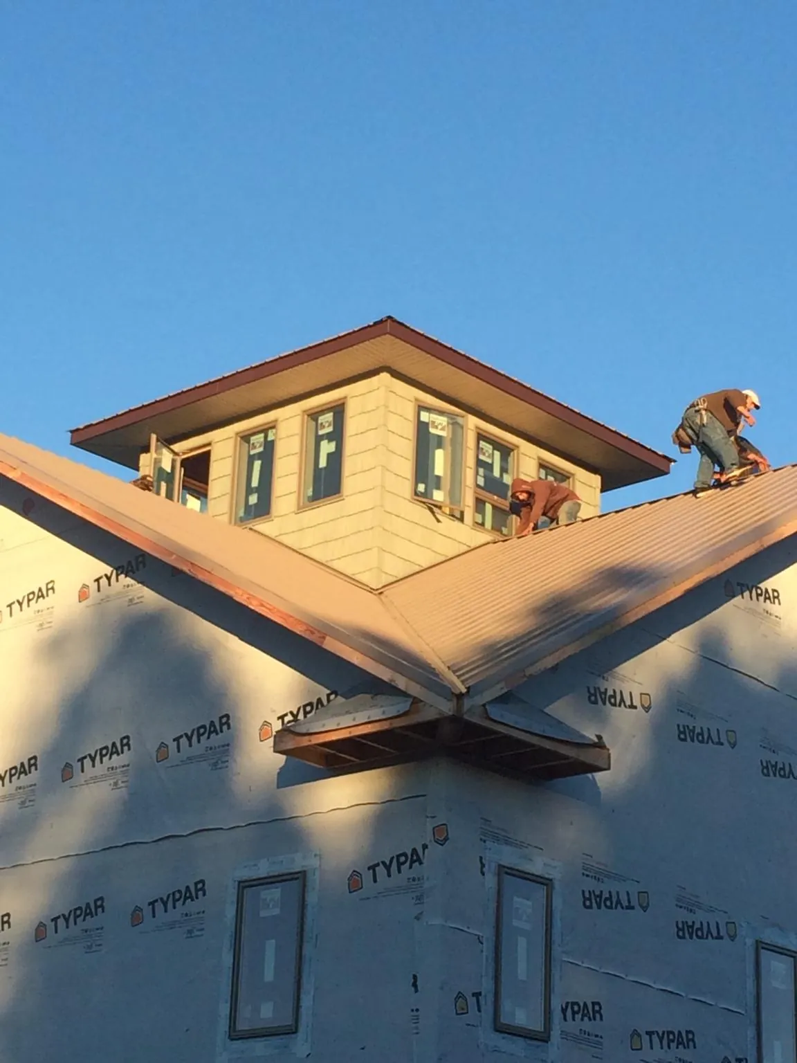 Roofers working around a rooftop cupola on a new metal roof at sunset — Roof Waterproofing in Saint Clairsville by Roofing Brothers